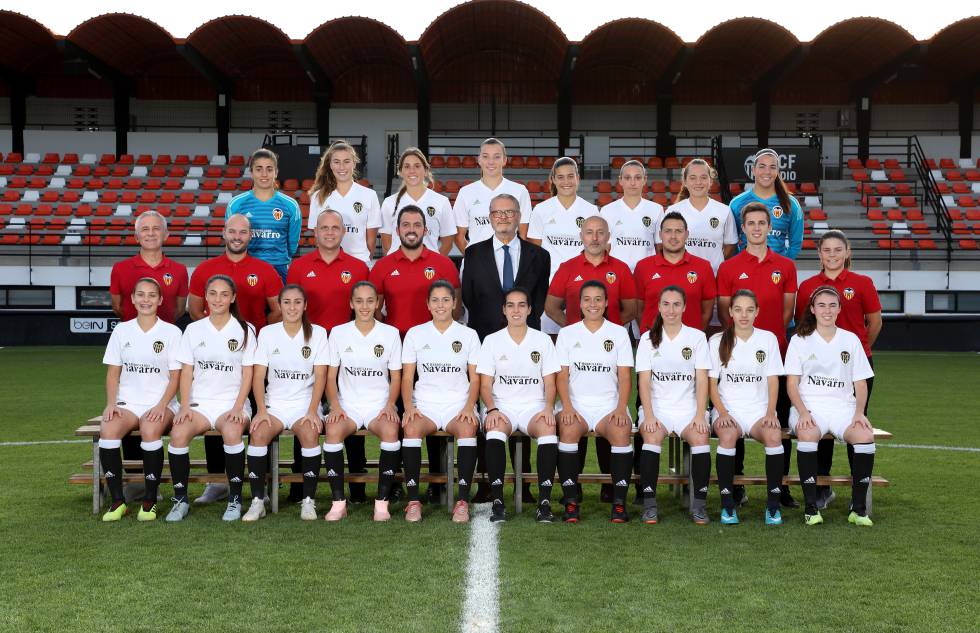 Foto oficial del equipo filial del Valencia FC, el mejor clasificado en la tabla, junto a las jugadoras de Liga Iberdrola Mari Paz, Gio Carreras, Paula Nicart, Sara Medina, Marta Peiró y Mandy van den Berg. Jesús Oliva y Sergio Fernández, coordinadores de la cantera, se sitúan a la derecha de Pedro Malabia, presidente de Honor (de traje).