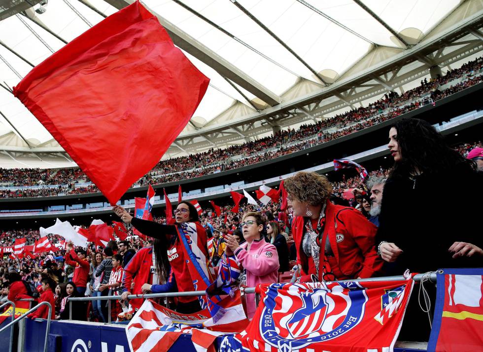 Torcedoras do Atlético de Madrid exibem bandeiras alvirrubras nas arquibancadas.