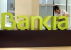 Una trabajadora limpia el logo de Bankia
