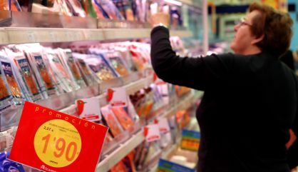 Una mujer mira un producto en un lineal de un supermercado.