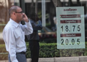 Un hombre habla por celular junto a una ventanilla bancaria.