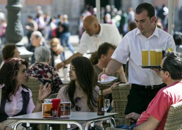 Un camarero sirve bebidas en una terraza en la plaza de la Virgen de Valencia.