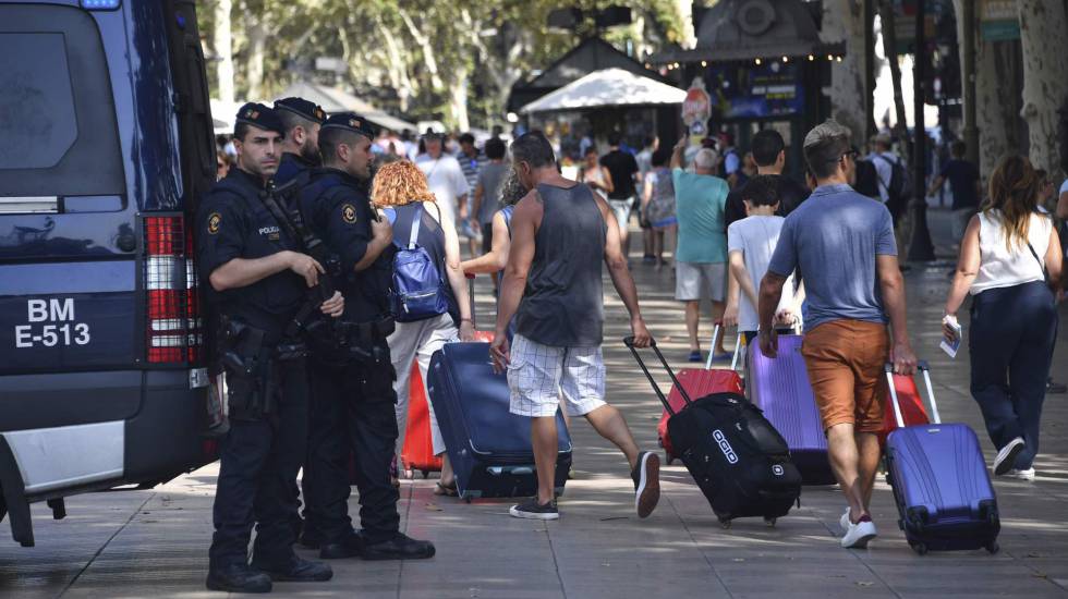 Turistas con maletas ante agentes de policía en La Rambla de Barcelona.