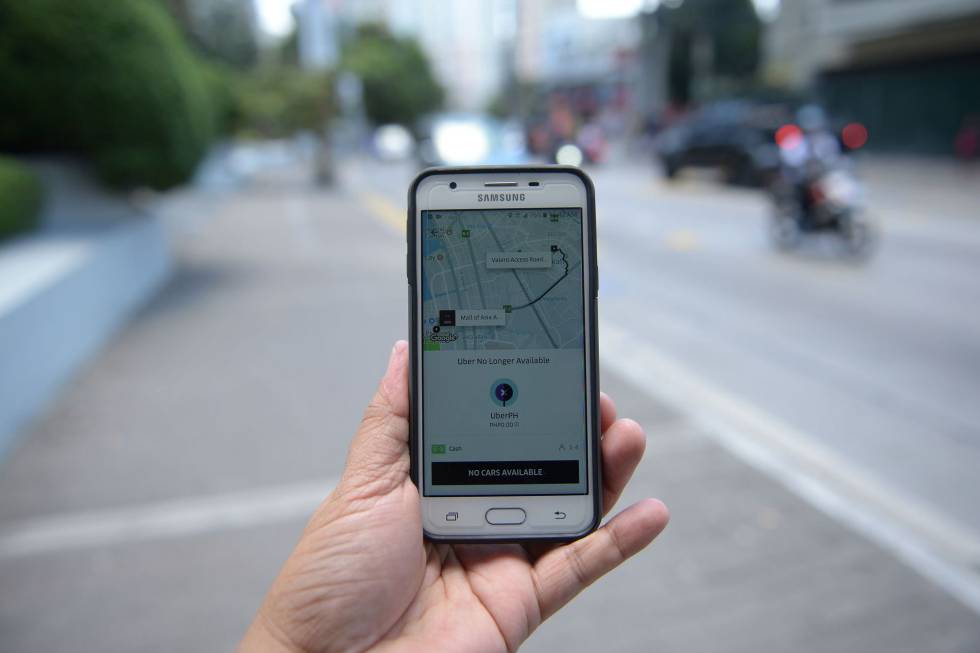 Un hombre sostiene un teléfono con la aplicación Uber