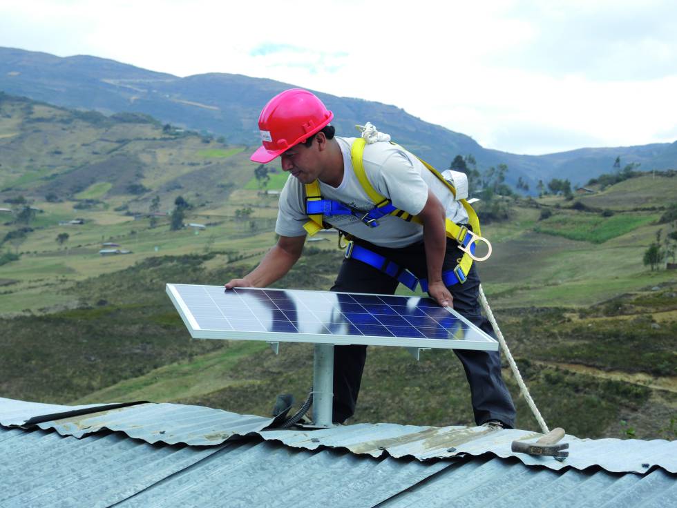 Un operario local instala un panel solar en el tejado de una vivienda.