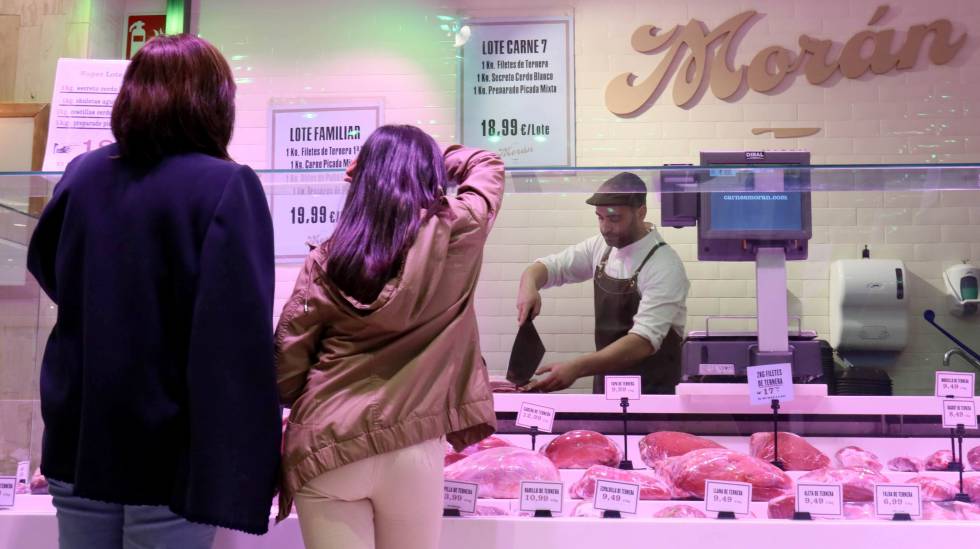 Un carnicero atiende a unas clientas en una galería comercial de Madrid.