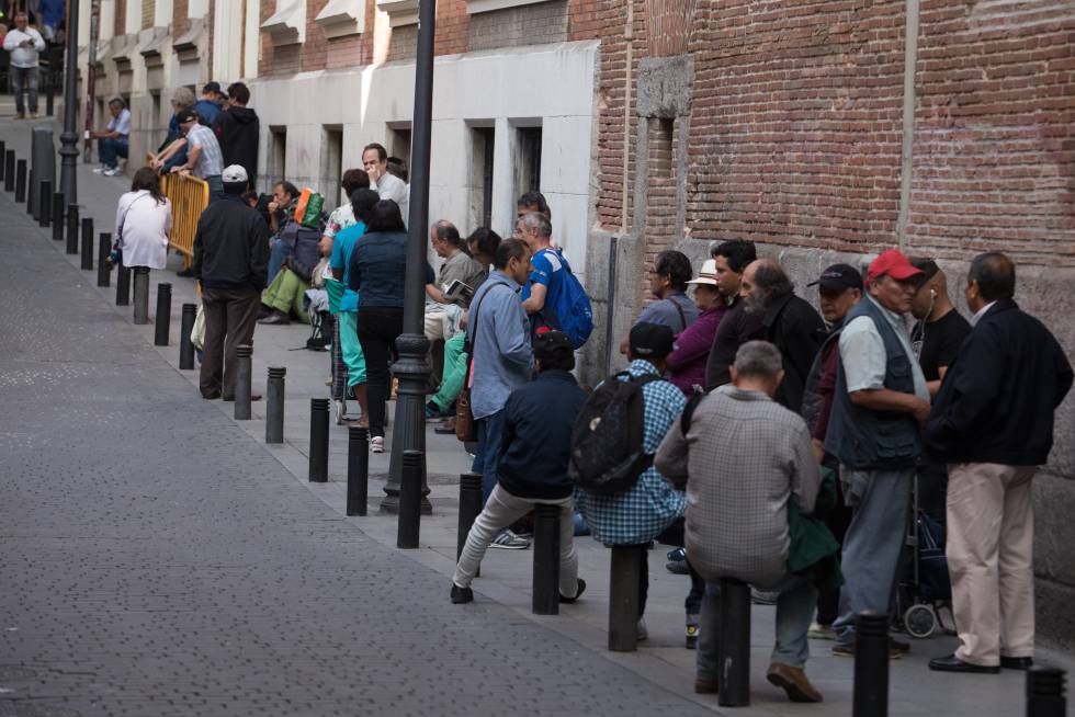 Un grupo de personas hace cola para entrar en un comedor social en Madrid