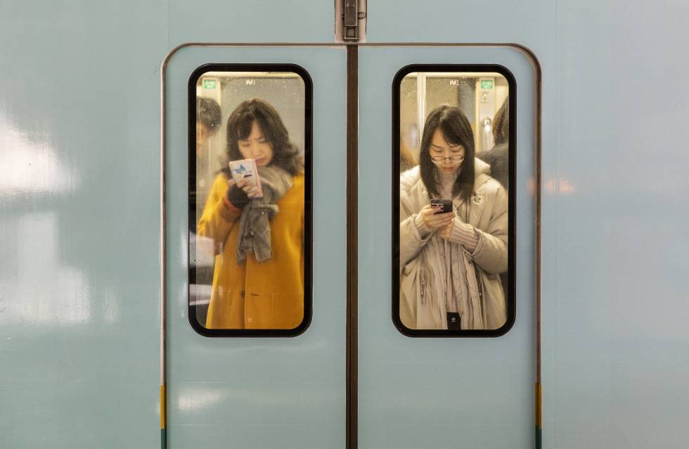 Dos mujeres consultan sus telÃ©fonos mÃ³viles mientras viajan en el metro de la ciudad de Chongqing (China).Â 