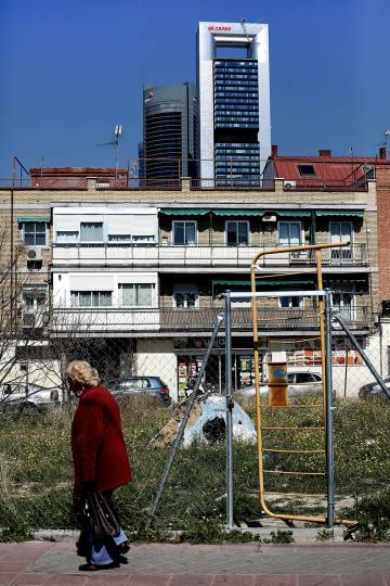 Una mujer pasea por el barrio de Tetuán, al fondo el área de negocios conocida como Cuatro Torres.