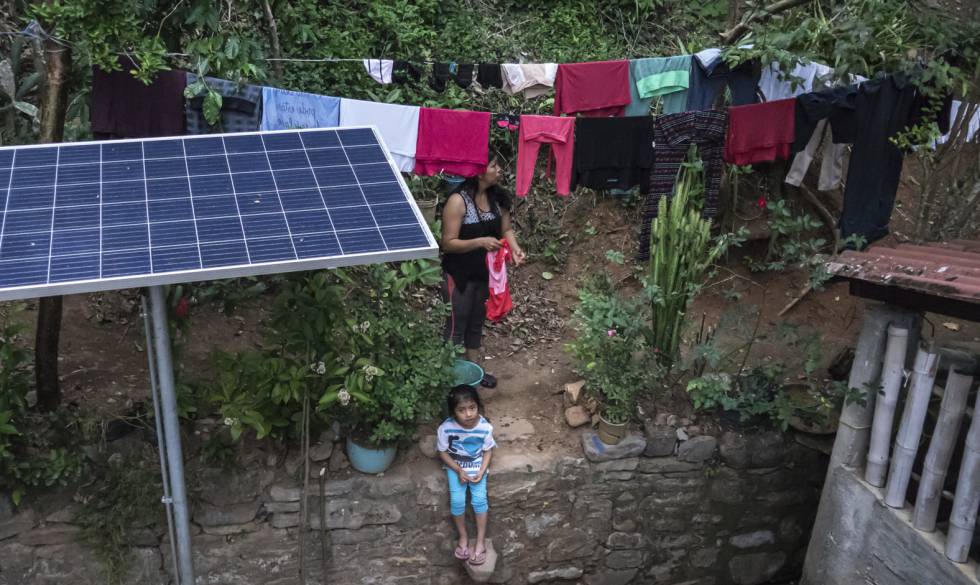 Una mujer tiende la ropa junto a un panel solar recién instalado en Zicuilapa.