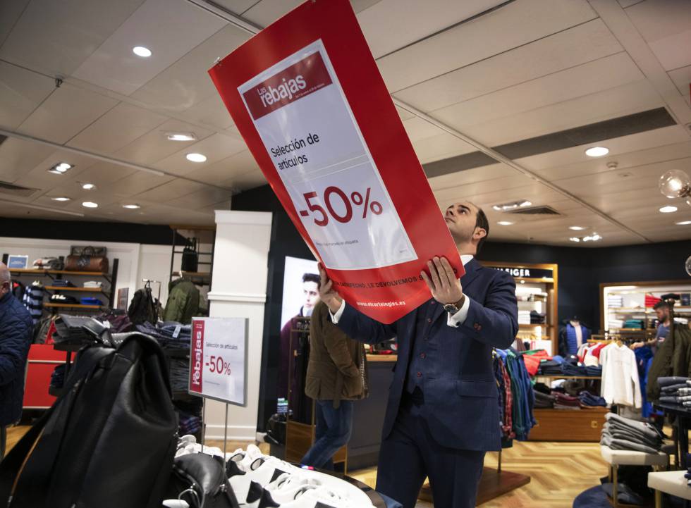 An employee of El Corte Inglés places a discount sign.