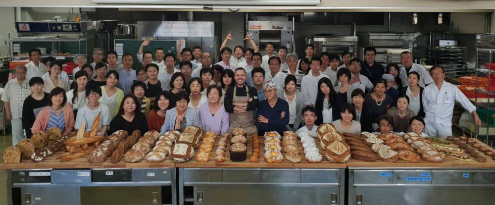 El chef Yohan Ferrant, en el Japan Institute of Baking (Tokio) con algunos alumnos durante una 'master class' en 2018 y junto con una decena de panes elaborados con la harina de espelta de Palazuelos.
