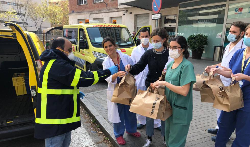 Un trabajador voluntario de Correos entrega comida a varios sanitarios de Madrid.