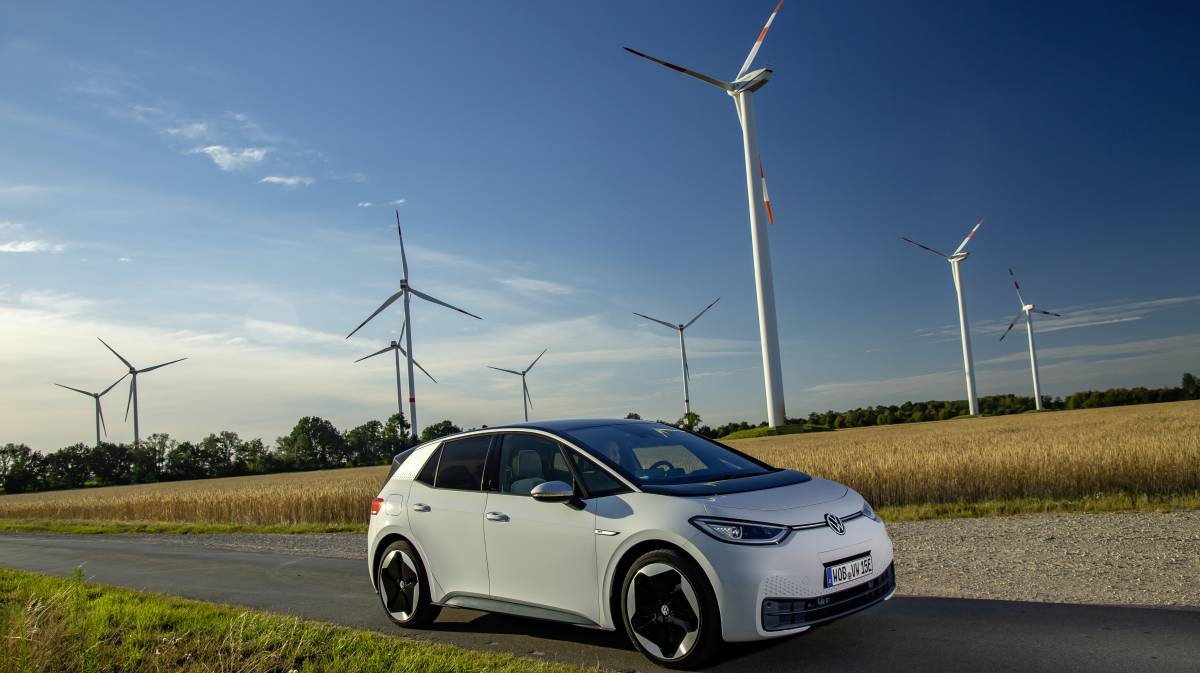 Un Volkswagen modelo ID.3 circula junto a un campo eólico.