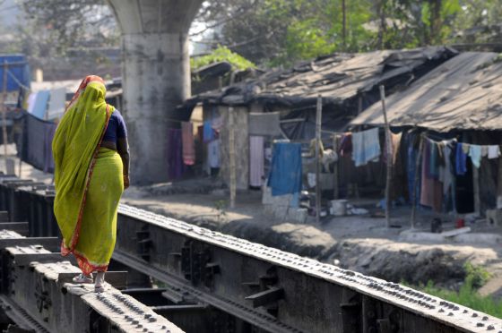Una mujer cruza un improvisado puente en una barriada de chabolas de Calcuta.