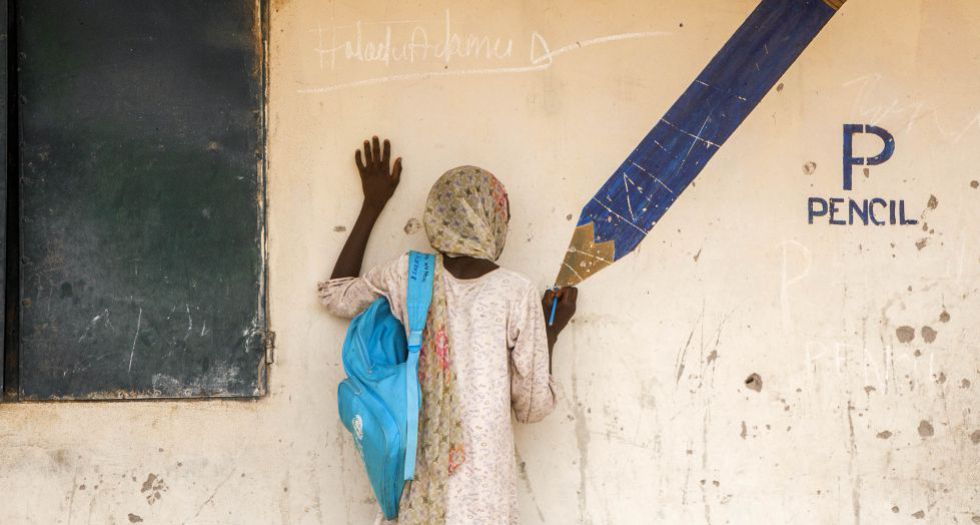 Aisha, de 13 años, usa un lápiz mientras finge dibujar en un mural del campo de Yola para desplazados internos. Cuando los miembros de Boko Haram atacaron su ciudad, Gwozo, mataron a su padre y secuestraron a su madre. Ella logró escapar y llegar al campo con su hermana mayor. Ahora cuidan la una de la otra. “Me gusta ir al cole aquí, pero quiero volver a mi pueblo”. Esiebo (Unicef)