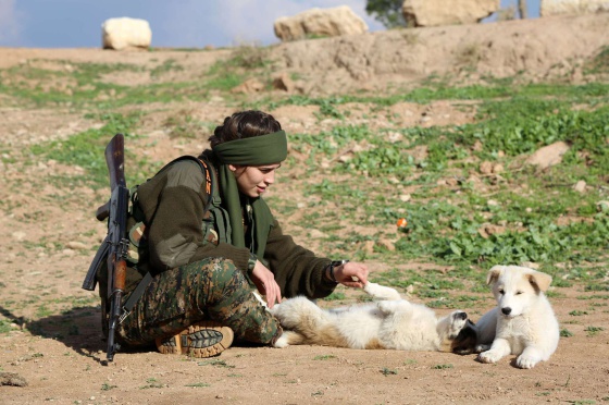 Una combatiente cristiana juega con dos perros en Al-Qahtaniyah (Siria)