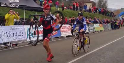 Ismael Esteban carries his bike as opponent Agustín Navarro follows.