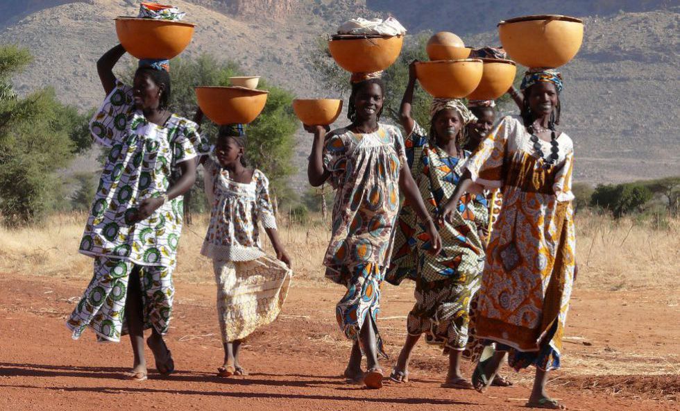 Mujeres de la tribu peul en Mali portan sobre sus cabezas grandes cuencos con ropa y leche.