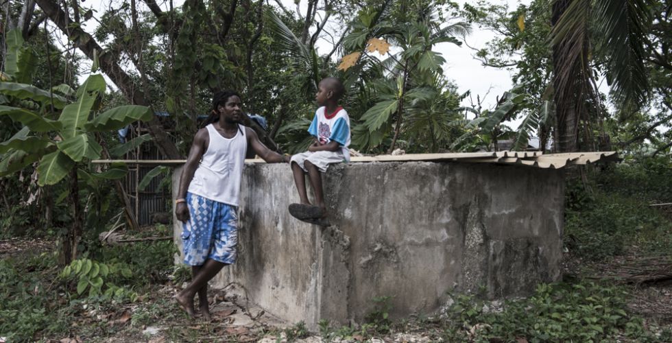 Ted y su hijo sentados sobre su cisterna, que no recoge agua de lluvia desde hace meses.