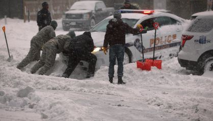 Varias personas sacan de la nieve un coche de polic&iacute;a en Washington.  