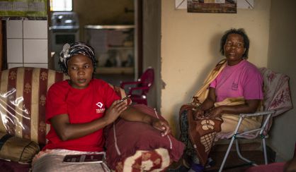 Auzan Zudide, enferma de tuberculosis en un poblado minero de Marikana (al fondo) y Thandiwe Nazimande, trabajadora social que la ayuda.