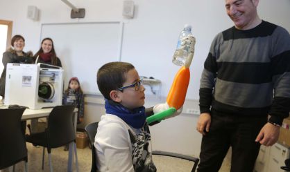 El ni&ntilde;o Unai Blanco agarra un botell&iacute;n de agua con su mano artificial realizada con una impresora 3D.