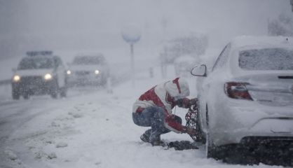 Un hombre coloca cadenas al coche en una carretera, cerca de Pedrafita do Cebreiro (Lugo).rn 