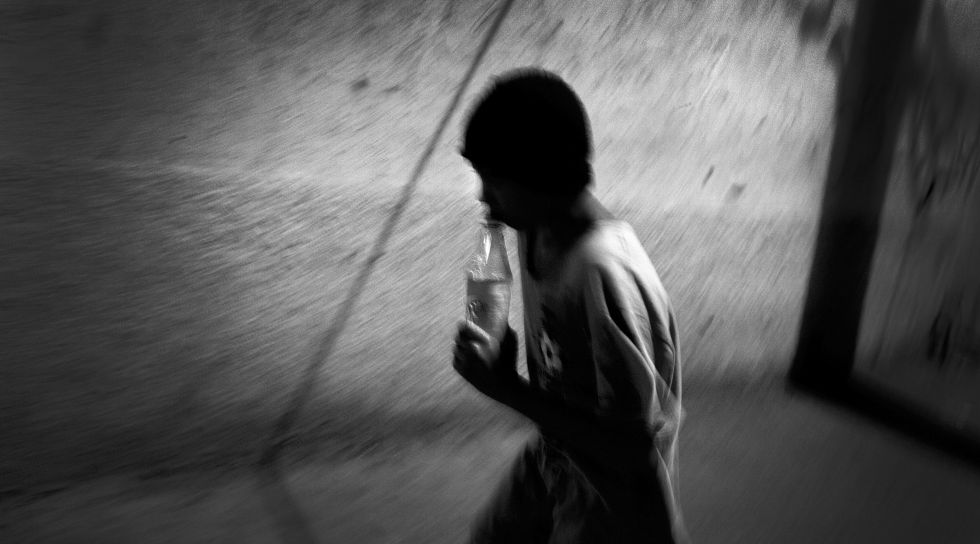 Una joven pasea por la calle inhalando pegamento en la capital de Honduras.