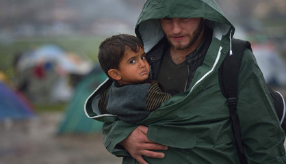 Un refugiado lleva en brazos a un niño pequeño en Idomeni.