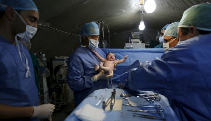 Un doctor marroqu&iacute; sostiene a un ni&ntilde;o sirio despu&eacute;s de una cesarea en el campo de refugiados Al Zaatar en Mafrag (Jordania).