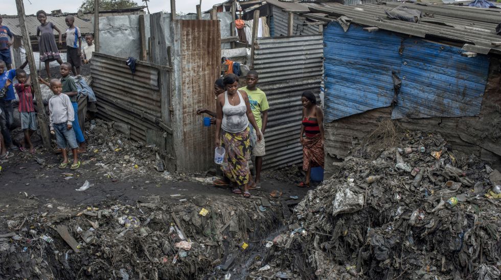 Una familia frente a su chabola en un asentamiento ilegal en la Comuna de Limete.