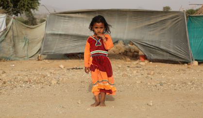 Una ni&ntilde;a permanece de pie frente a su tienda en el campo para desplazados de Shawqaba, en Yemen.