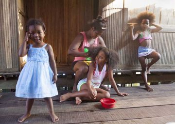 Una madre con sus hijas frente a su casa.