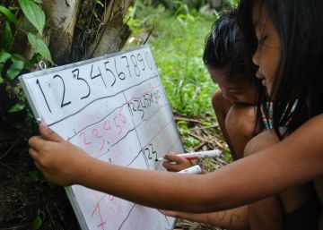Dos ni&ntilde;os Orang Rimba escriben n&uacute;meros en una pizarra.