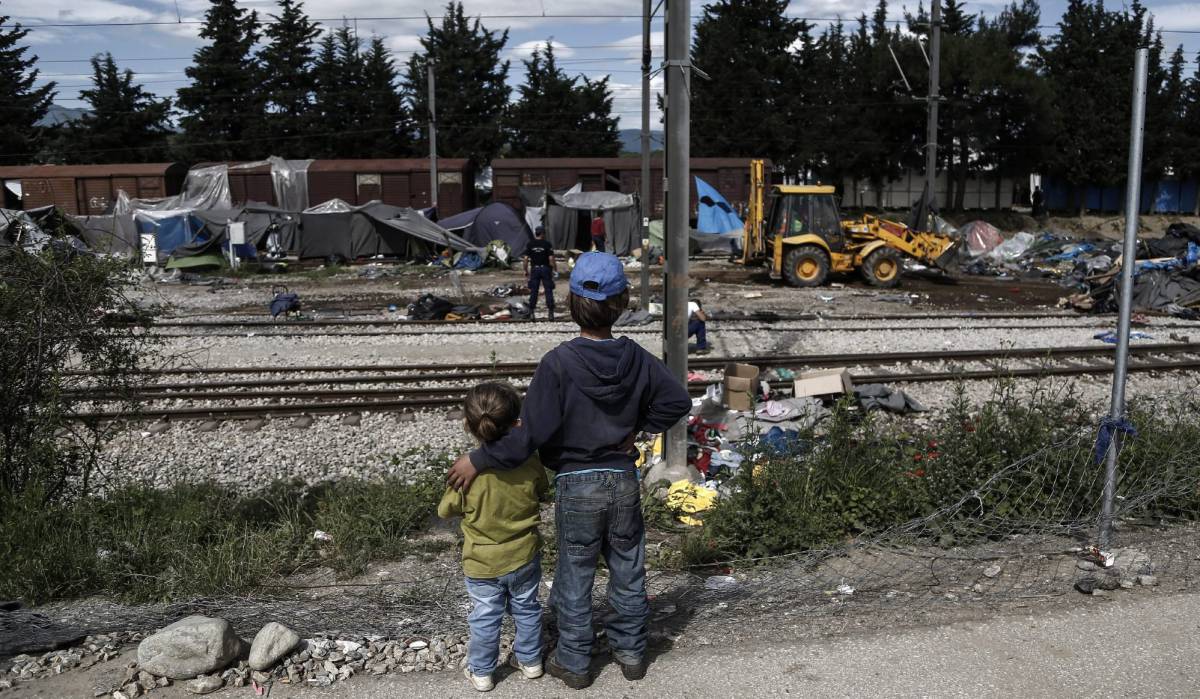 Dos ni&ntilde;os observan el desmantelamiento del campo de refugiados de Idomeni, en Grecia.