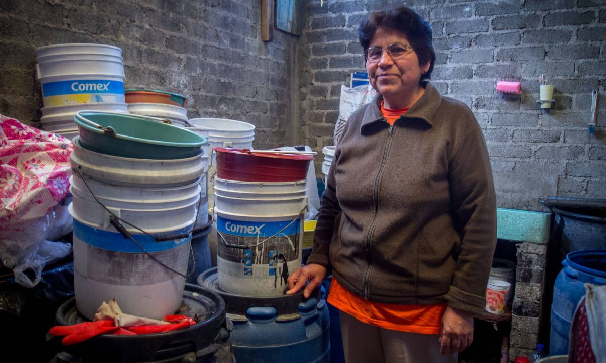 Una mujer con los cubos que usa para recoger agua de lluvia.