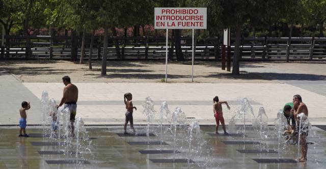 Un grupo de personas se refrescan en las fuentes verticales del parque Juan Carlos I, en Madrid.