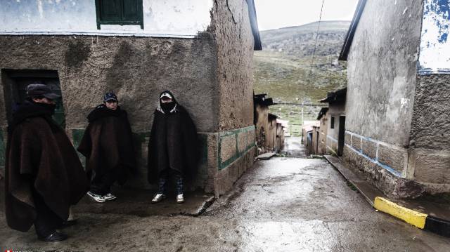 Tres hombres se protegen del fr&iacute;o en los Andes peruanos.