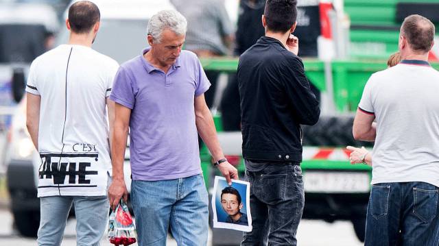 The father of a victim, center, hlds a picture of his son near the Olympia shopping center where a shooting took place leaving nine people dead the day before on Saturday, July 23, 2016 in Munich, Germany. (AP PhotoSebatian Widmann)