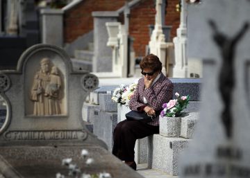 Una mujer reflexiona sentada sobre una tumba en el cementerio.