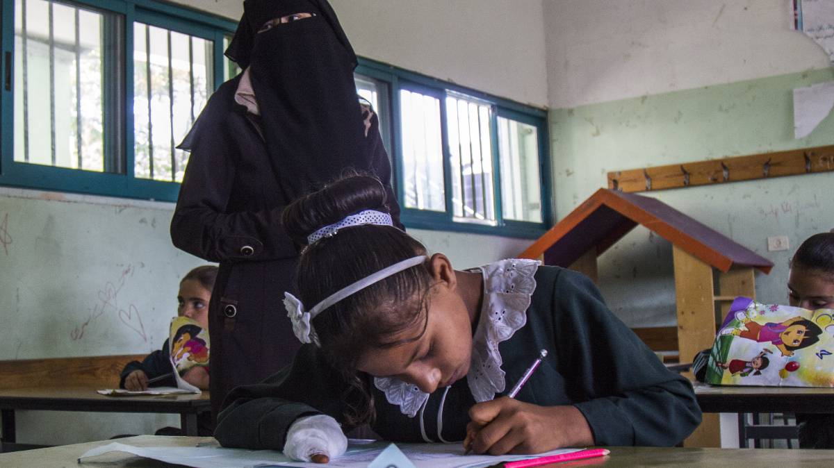 Doaa, con la mano vendada, hace los deberes en el colegio.