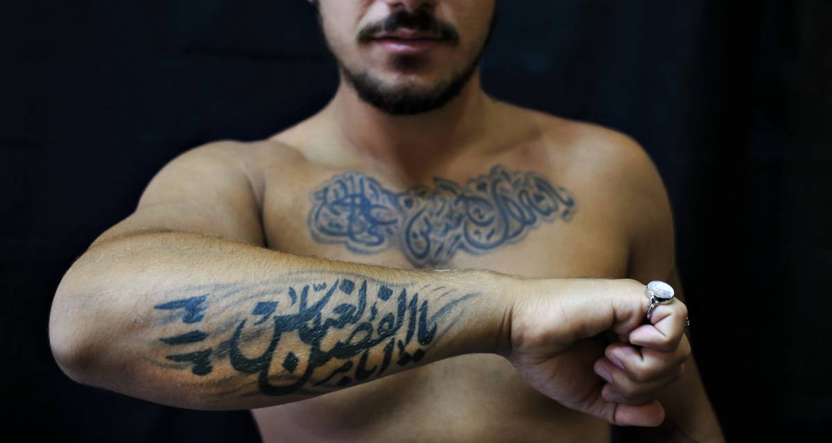 Alodi Issa, 22 años, muestra sus tatuajes con eslógans musulmanes chiítas, en el sur de Beirut, Líbano.