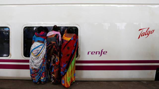 Tres mujeres miran por una venta de un tren de alta velocidad Talgo, en Bombay.