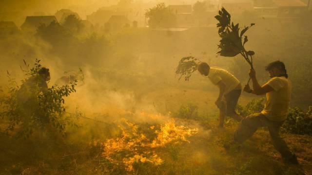 Vecinos de la parroquia de Acevedo (Pontevedra) luchan contra el fuego que rodea sus casas.