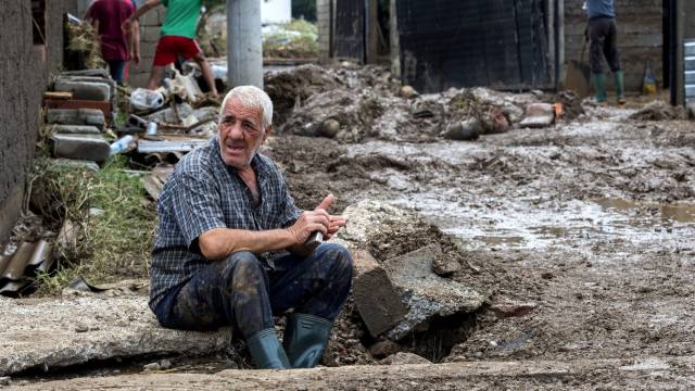 Un anciano descansa mientras sus vecinos limpian sus casas inundadas en el pueblo Stajkovci de Skopie.