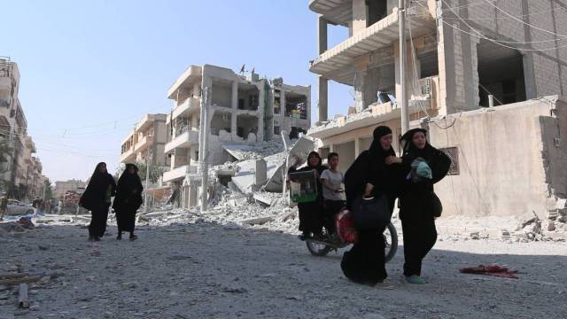 Mujeres sirias reaccionan mientras caminan por una calle después de ser evacuadas.