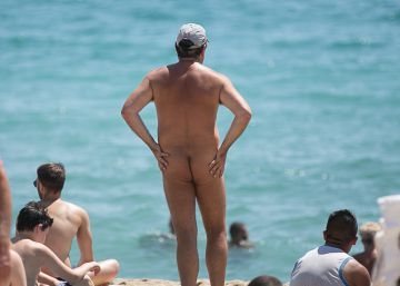 Un nudista en la playa de la Mar Bella rodeado de personas en traje de ba&ntilde;o.