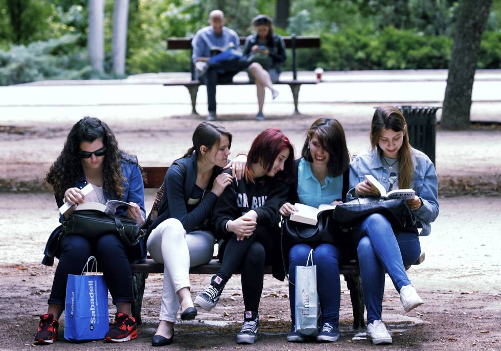 Un grupo de jóvenes lee en un banco en la Feria del Libro de Madrid.