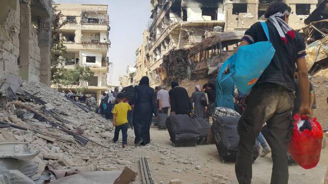 Ciudadanos sirios llevan sus pertenencias mientras se preparan para ser evacuados de Daraya.